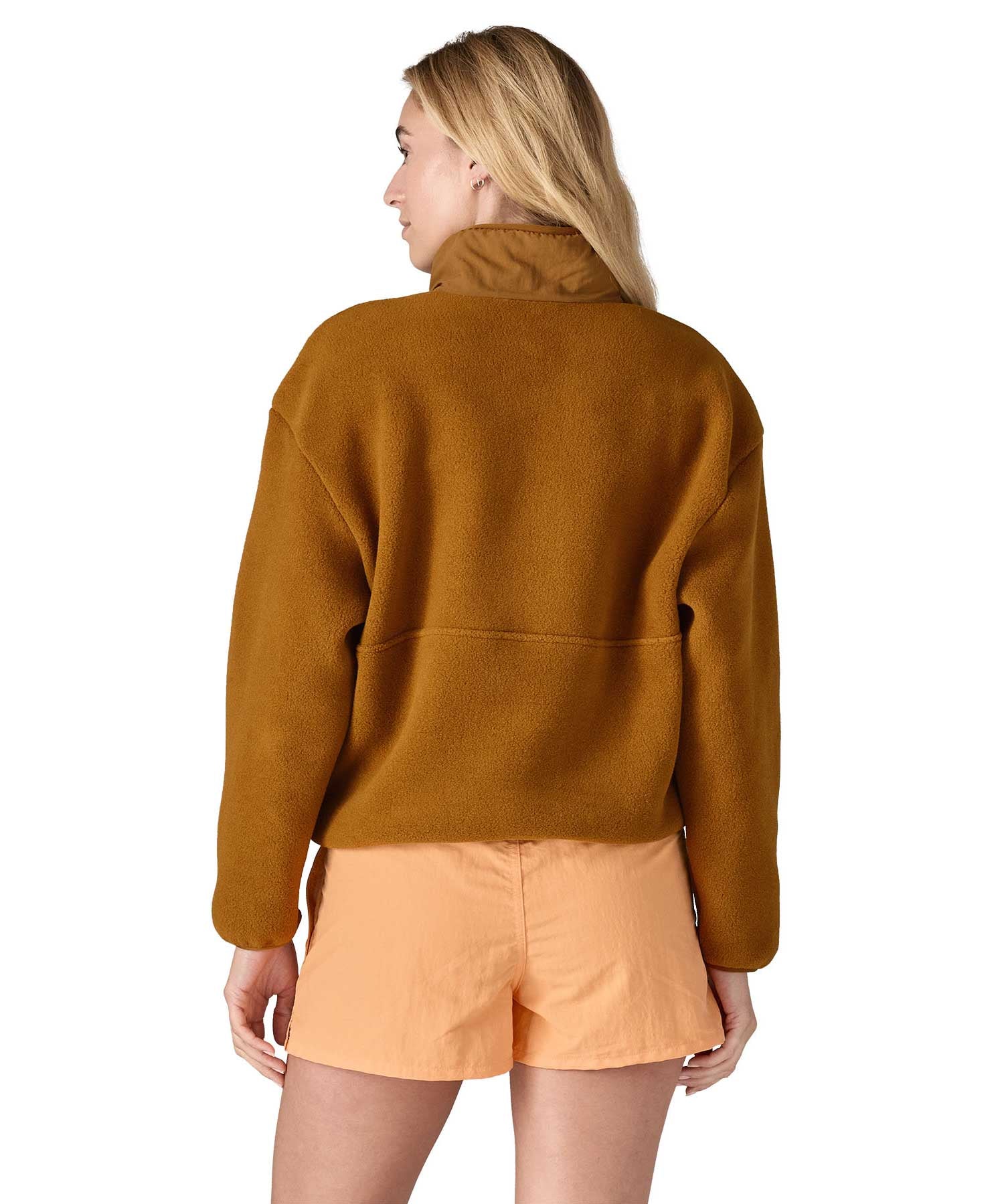 A woman wearing a mustard yellow coloured Patagonia Women's Synchilla Fleece Marsupial Pullover showing the back of the top.