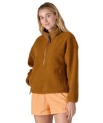 A woman wearing a mustard yellow coloured Patagonia Women's Synchilla Fleece Marsupial Pullover.