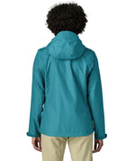 Back of a women wearing the Patagonia women's waterproof torrentshell 3L rain jacket in glacial blue.