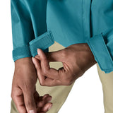 Close up of a women wearing the Patagonia women's waterproof torrentshell 3L rain jacket in glacial blue adjusting the velcro on the adjustable cuffs.