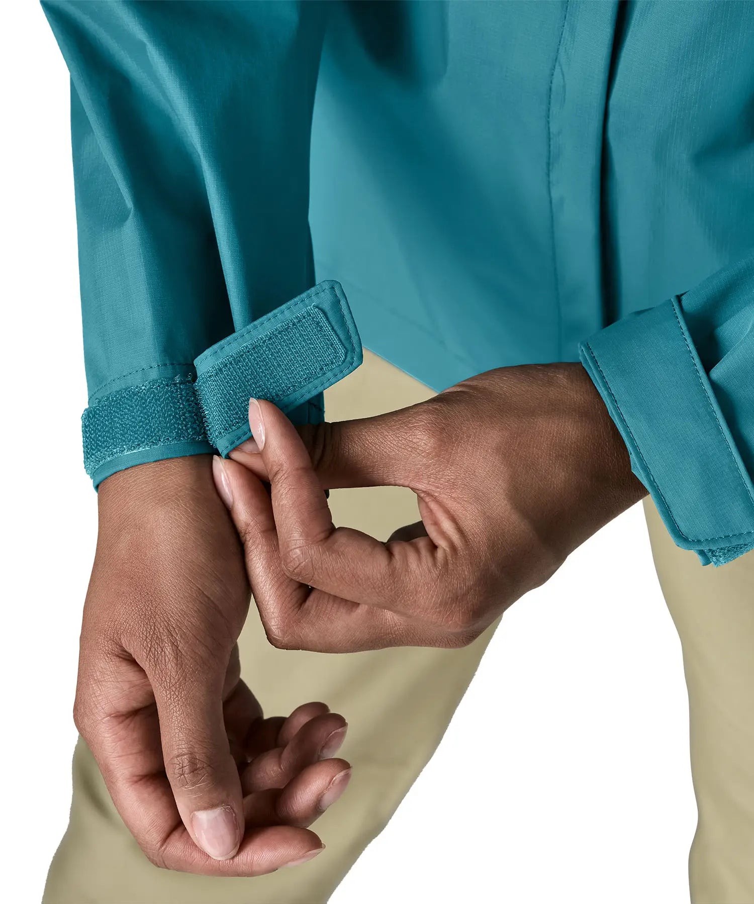 Close up of a women wearing the Patagonia women's waterproof torrentshell 3L rain jacket in glacial blue adjusting the velcro on the adjustable cuffs.