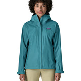 Woman wearing the Patagonia women's waterproof torrentshell 3L rain jacket in glacial blue with the front zip fully closed.