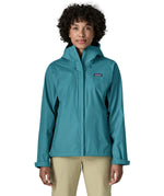 Woman wearing the Patagonia women's waterproof torrentshell 3L rain jacket in glacial blue with the front zip fully closed.