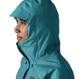 Close up of a womanwearing the Patagonia women's waterproof torrentshell 3L rain jacket in glacial blue with the hood up.