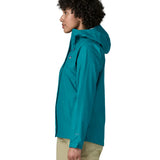 Side of a women wearing the Patagonia women's waterproof torrentshell 3L rain jacket in glacial blue.