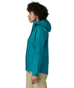 Side of a women wearing the Patagonia women's waterproof torrentshell 3L rain jacket in glacial blue.
