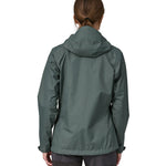 A woman wearing a Patagonia Women's Torrentshell 3L Rain jacket in a Nouveau Green showing the back