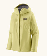 Patagonia women's waterproof torrentshell 3L rain jacket in light vellum green with adjustable hood, zippered handwarmer pockets.