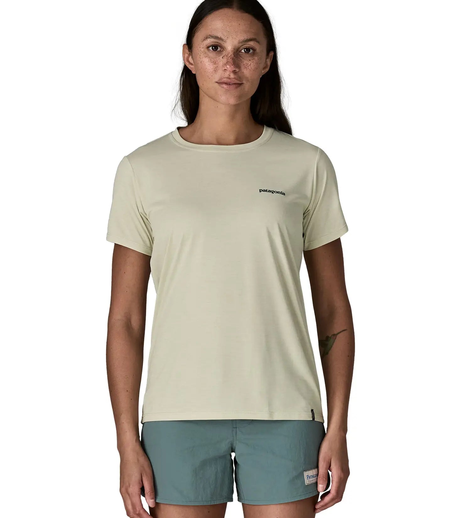 Woman wearing Patagonia's women's white quick drying capilene short sleeve t-shirt with small brand text logo on the chest. T-shirt has a relaxed fit