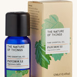 Patchouli pure essential oil in a blue glass bottle in front of a decorative cream cardboard box.