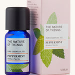 Organic Peppermint pure essential oil in a blue glass bottle in front of a decorative pink cardboard box.