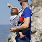 An adult carrying a baby in the Love Radius PhysioCarrier in Elephant.