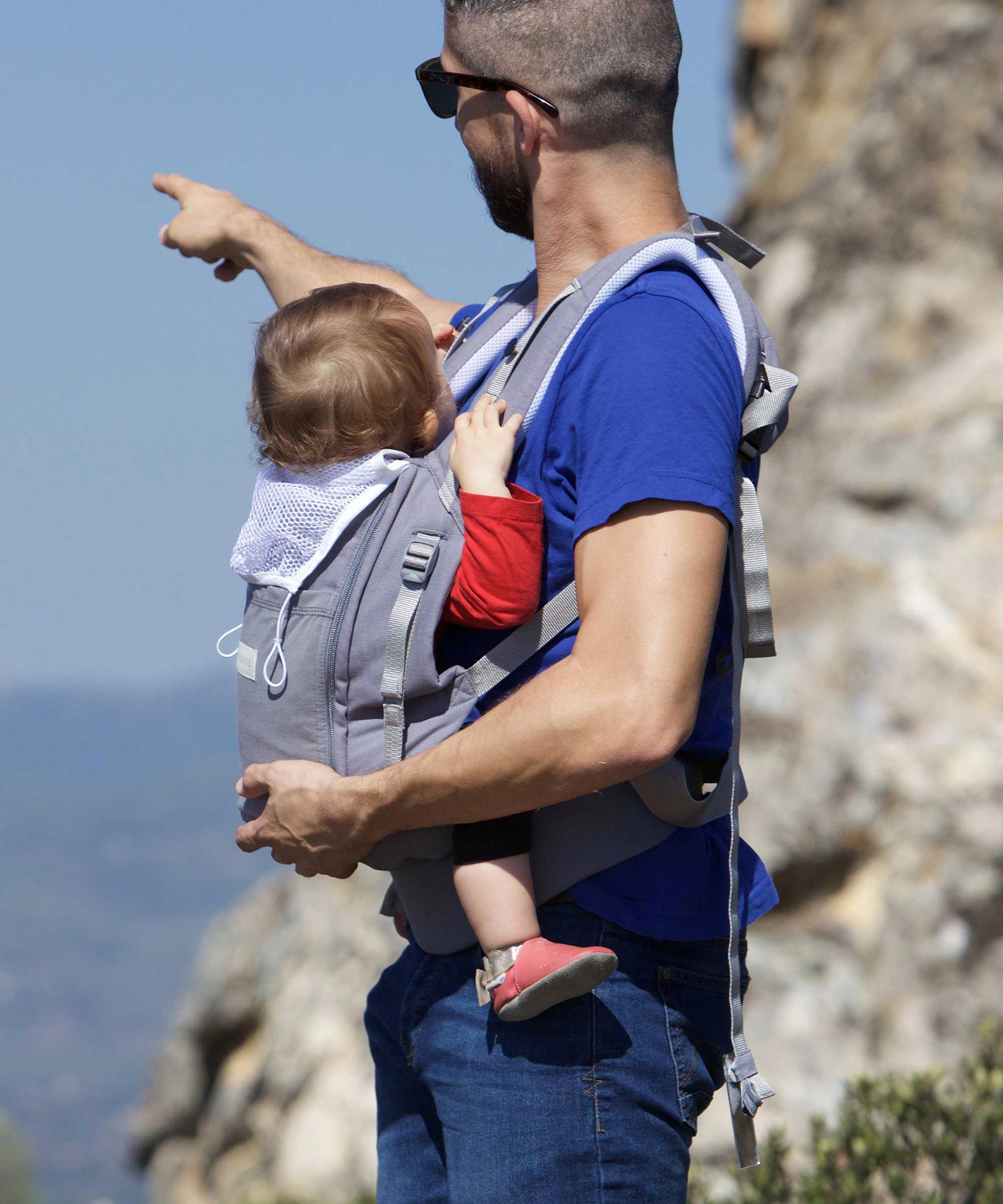 An adult carrying a baby in the Love Radius PhysioCarrier in Elephant.