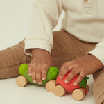 A child wheeling the Oli & Carol Sweetie The Strawberry Baby Car in their hand