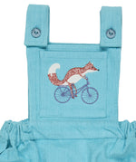 A close up of the cycling fox embroidery from the Pigeon Organics turquoise corduroy pinafore dress available at Babipur showing the button fastener detail on the shoulder straps 