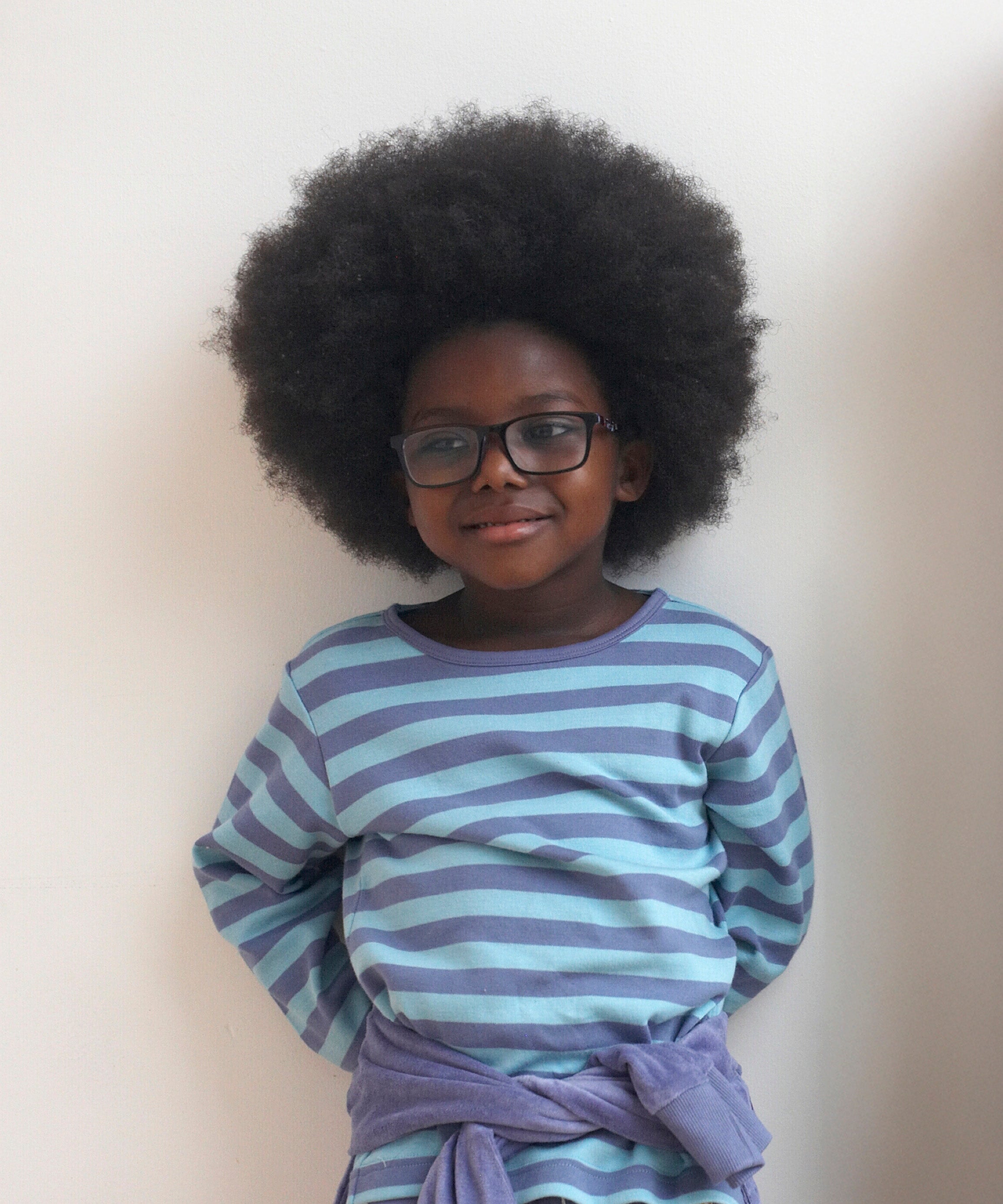 A child wearing the Pigeon Organics long sleeve top showing the light and dark blue striped design on organic cotton fabric