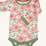 Pigeon Organics large floral body - GOTS organic cotton baby body in a light neutral colour with a pale green trim, long sleeves and popper fasteners at the crotch for easy fitting. Features multiple prints of a pink  flower and green leaves