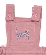 A close up of the pink cat embroidery from the Pigeon Organics corduroy pinafore dress available at Babipur showing the button fastener detail on the shoulder straps 