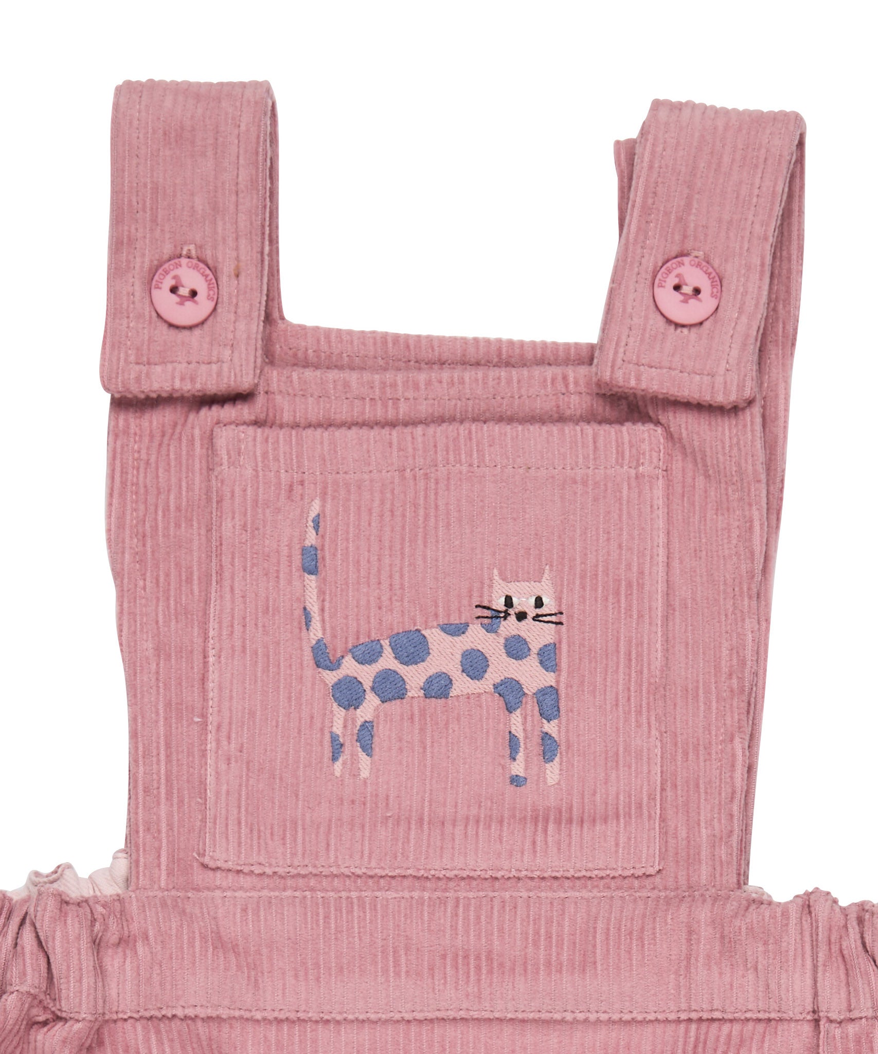 A close up of the pink cat embroidery from the Pigeon Organics corduroy pinafore dress available at Babipur showing the button fastener detail on the shoulder straps 