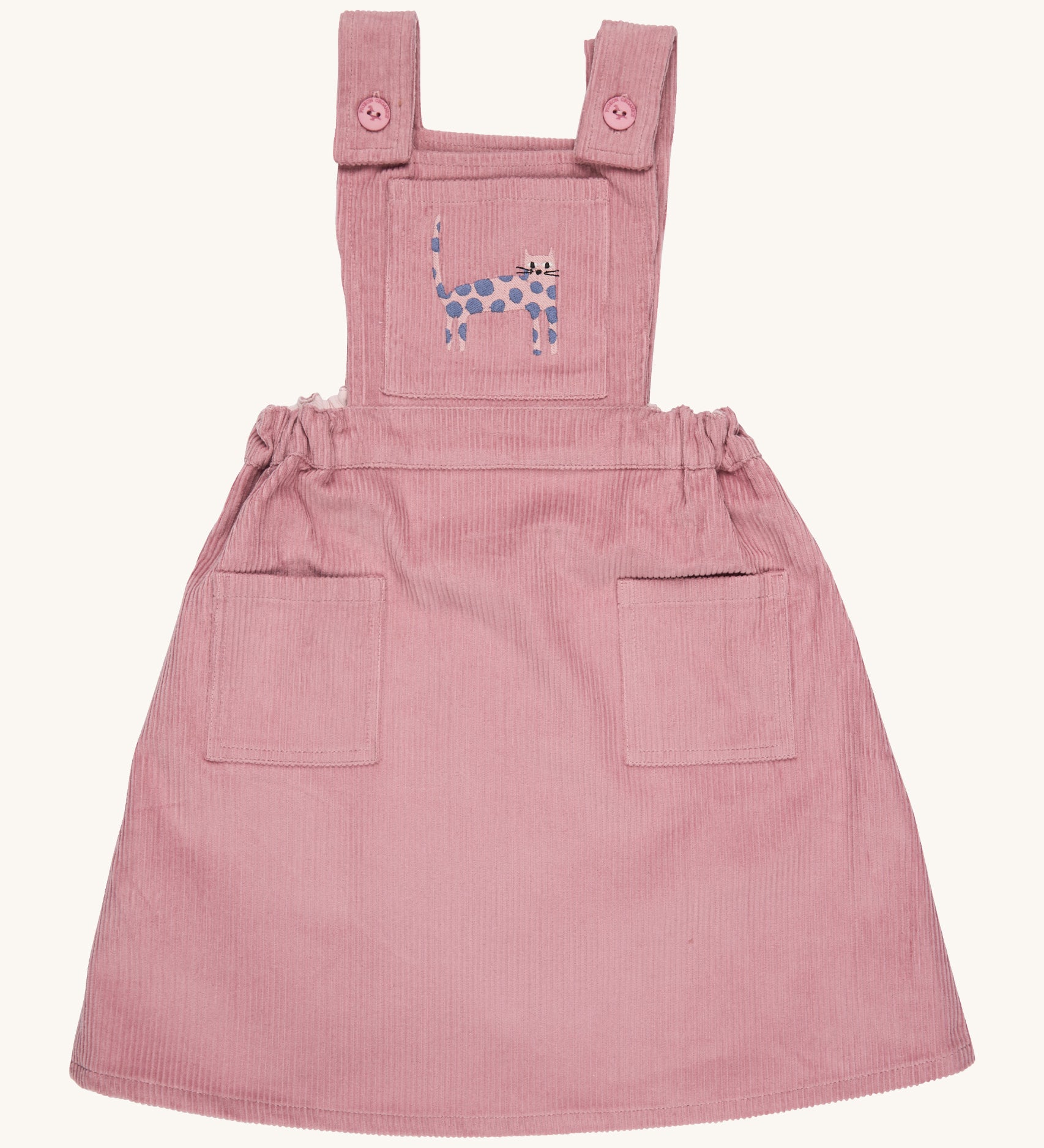 Pigeon Organics pinafore- GOTS organic cotton pinafore sleeves dress in pink corduroy. Features 2 small pockets at the front, button fasteners on the shoulders, an elasticated waist band and a pink cat embroidery on the chest.