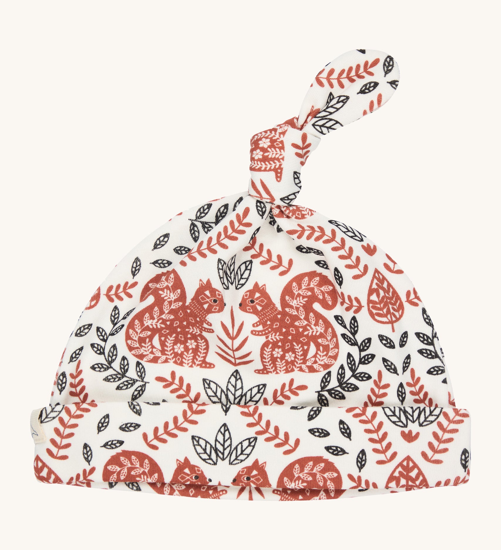 Pigeon Organics knotted baby hat - 100% GOTS organic neutral coloured cotton hat with a top knot. Features multiple artistic prints of a light brown squirrels and leaves