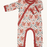 Pigeon Organics kimono romper. A 100% GOTS organic cotton in white with a pale rust trim showing the long sleeves and popper fasteners at the front and between the legs. Features a print of a artistic flowers and squirrels all over the garment. 