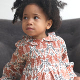 Close up of the Pigeon Organics squirrel smock dress worn by a toddler showing the soft elasticated waist band and collar detail.