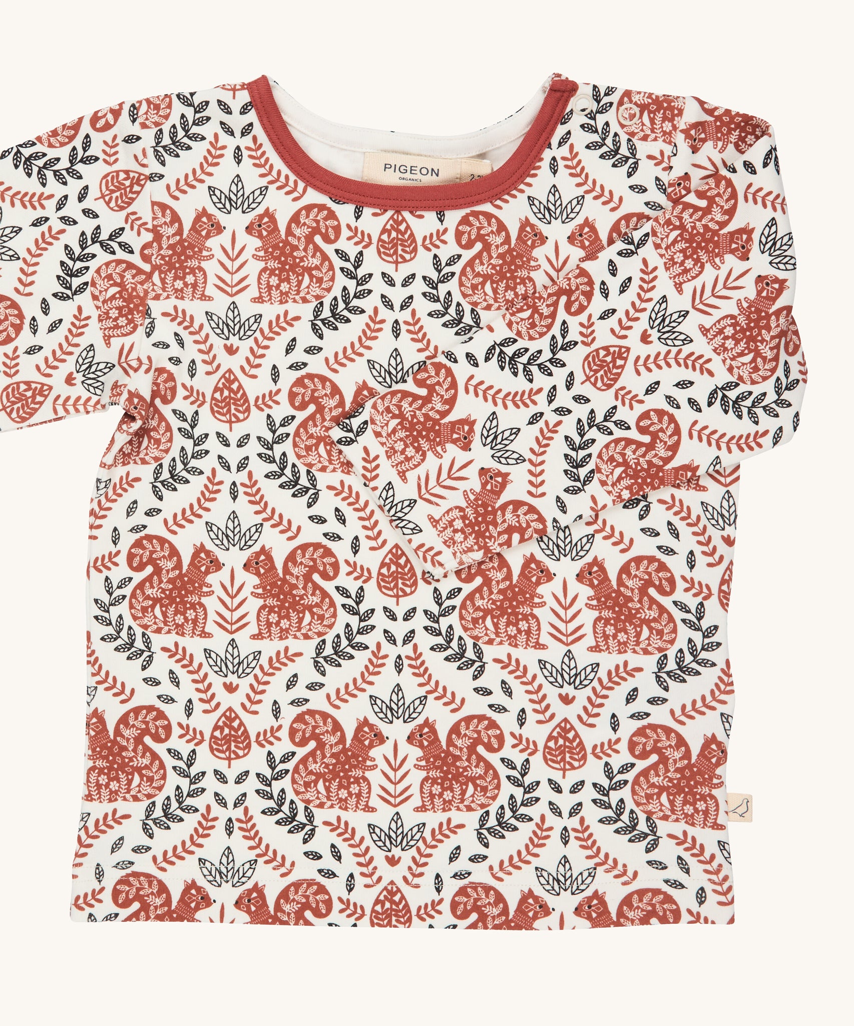 Pigeon Organics squirrel long sleeved top. A GOTS organic cotton t-shirt with long sleeves in a cream colour. Features a dark orange and black coloured print with squirrels and foliage.