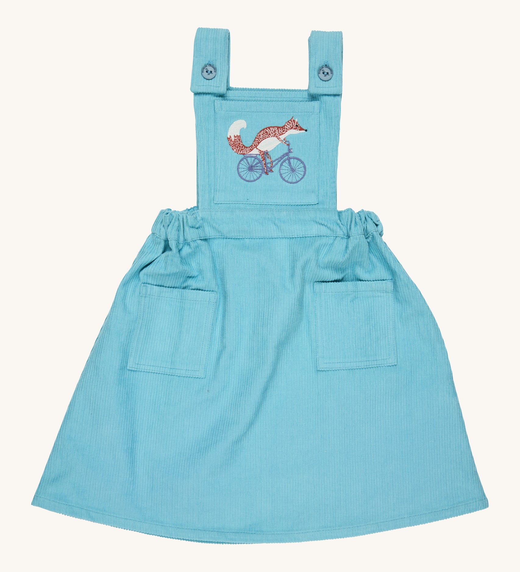 Pigeon Organics pinafore- GOTS organic cotton pinafore sleeves dress in turquoise corduroy. Features 2 small pockets at the front, button fasteners on the shoulders, an elasticated waist band and a fox riding a bike embroidery on the chest.