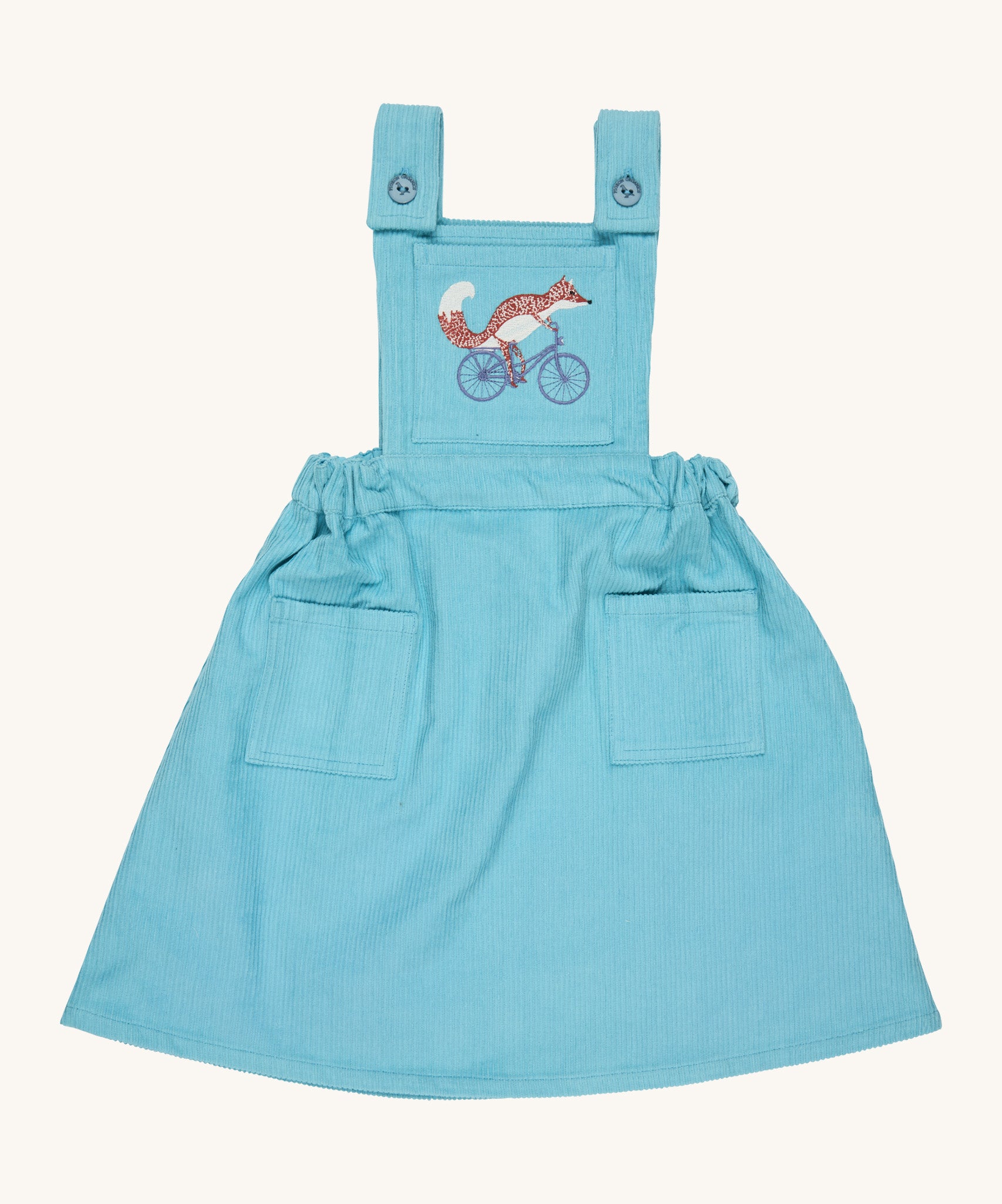 Pigeon Organics pinafore- GOTS organic cotton pinafore sleeves dress in turquoise corduroy. Features 2 small pockets at the front, button fasteners on the shoulders, an elasticated waist band and a fox riding a bike embroidery on the chest.