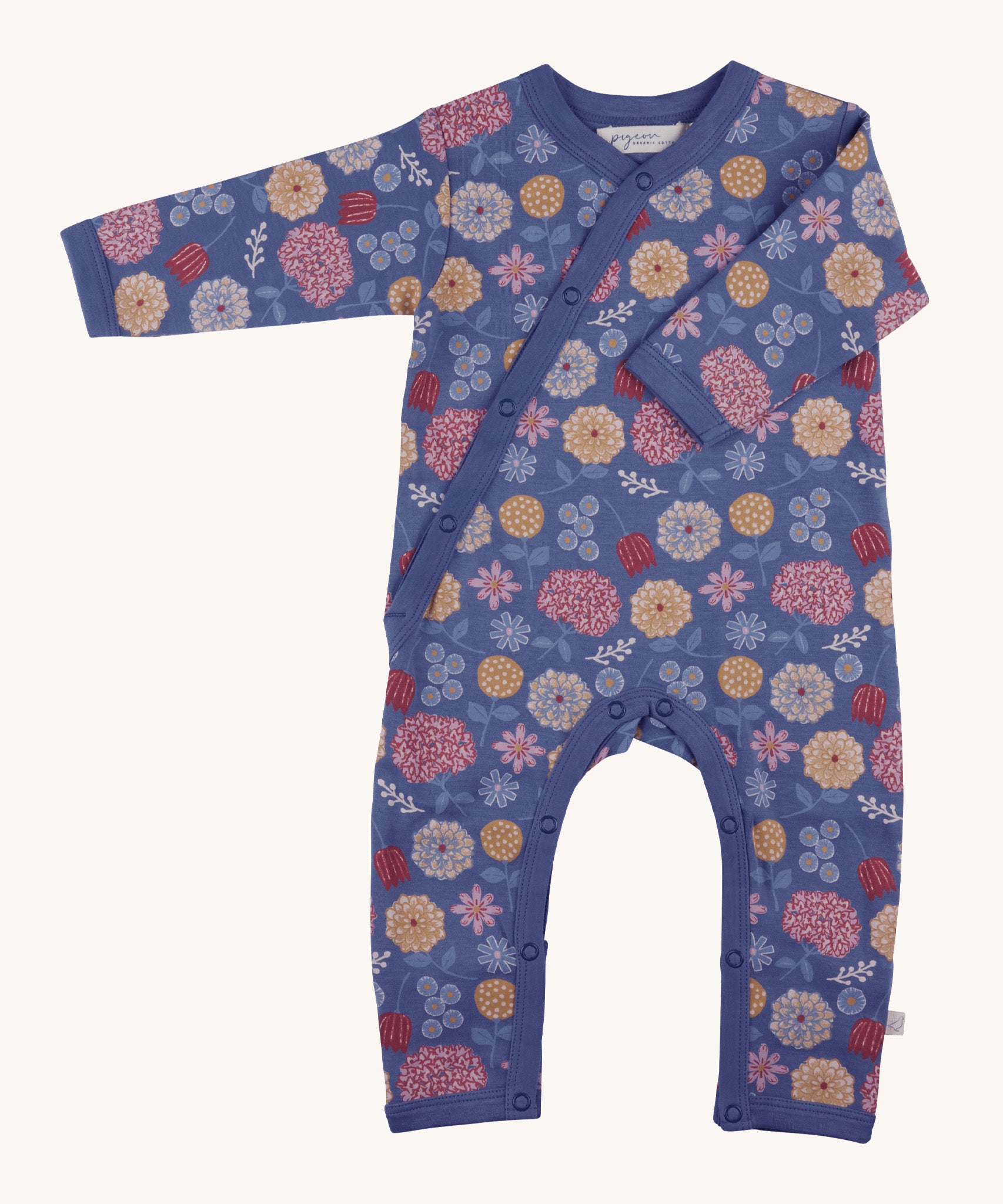 Pigeon Organics kimono romper. A 100% GOTS organic cotton in navy blue with long sleeves and popper fasteners at the front and between the legs. Features a print of multicoloured artistic flowers all over the garment. 