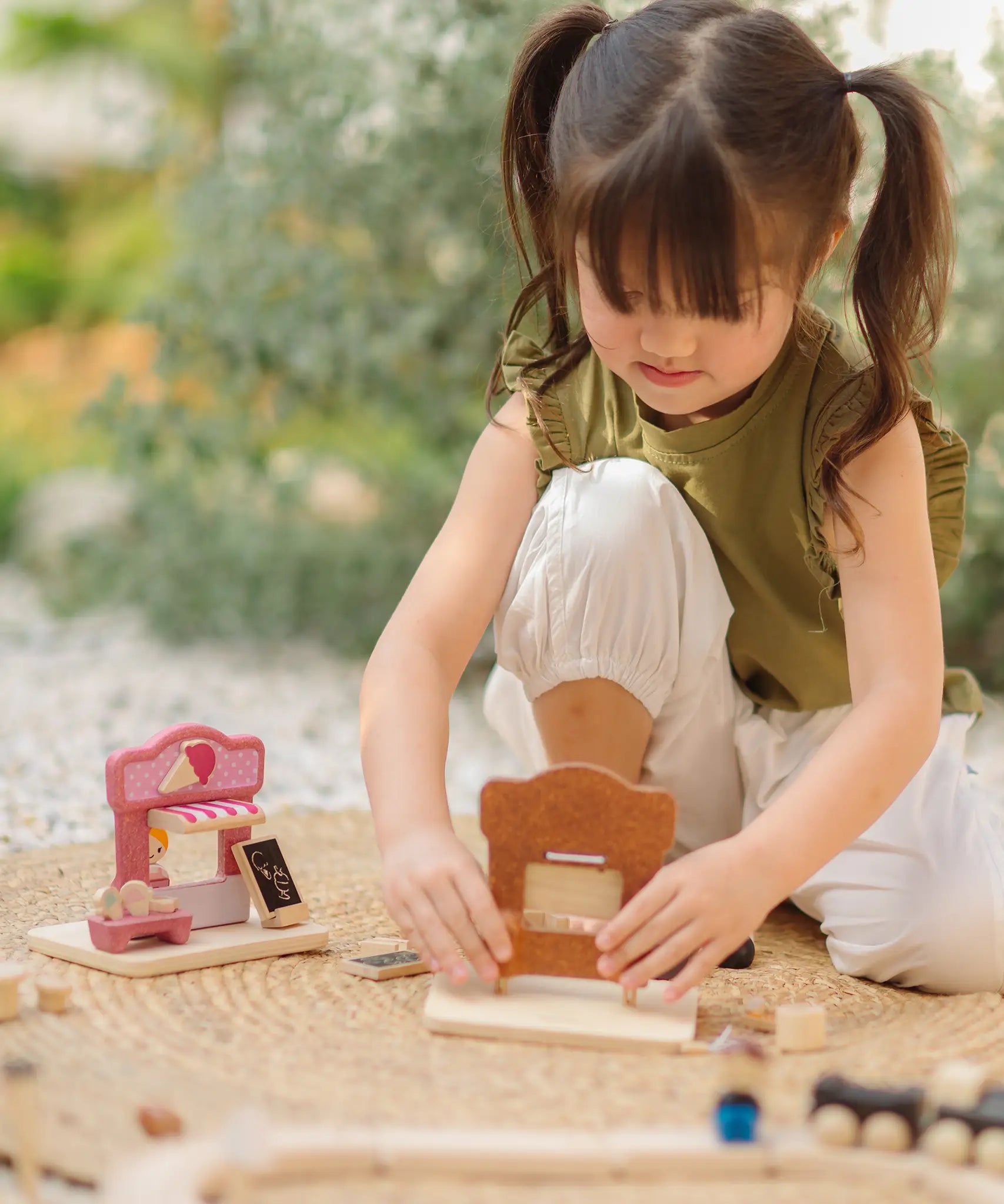 Child playing with the PlanToys bakery shop wooden toy playset and ice cream shop play set.