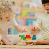 Children playing with the PlanToys balancing cargo wooden balance game. Stacking wooden blocks on the base piece. 