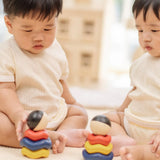 Two babies playing with two of the Baby playing with the PlanToys ball and wave stacker wooden baby stacking toys.