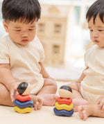 Two babies playing with two of the Baby playing with the PlanToys ball and wave stacker wooden baby stacking toys.
