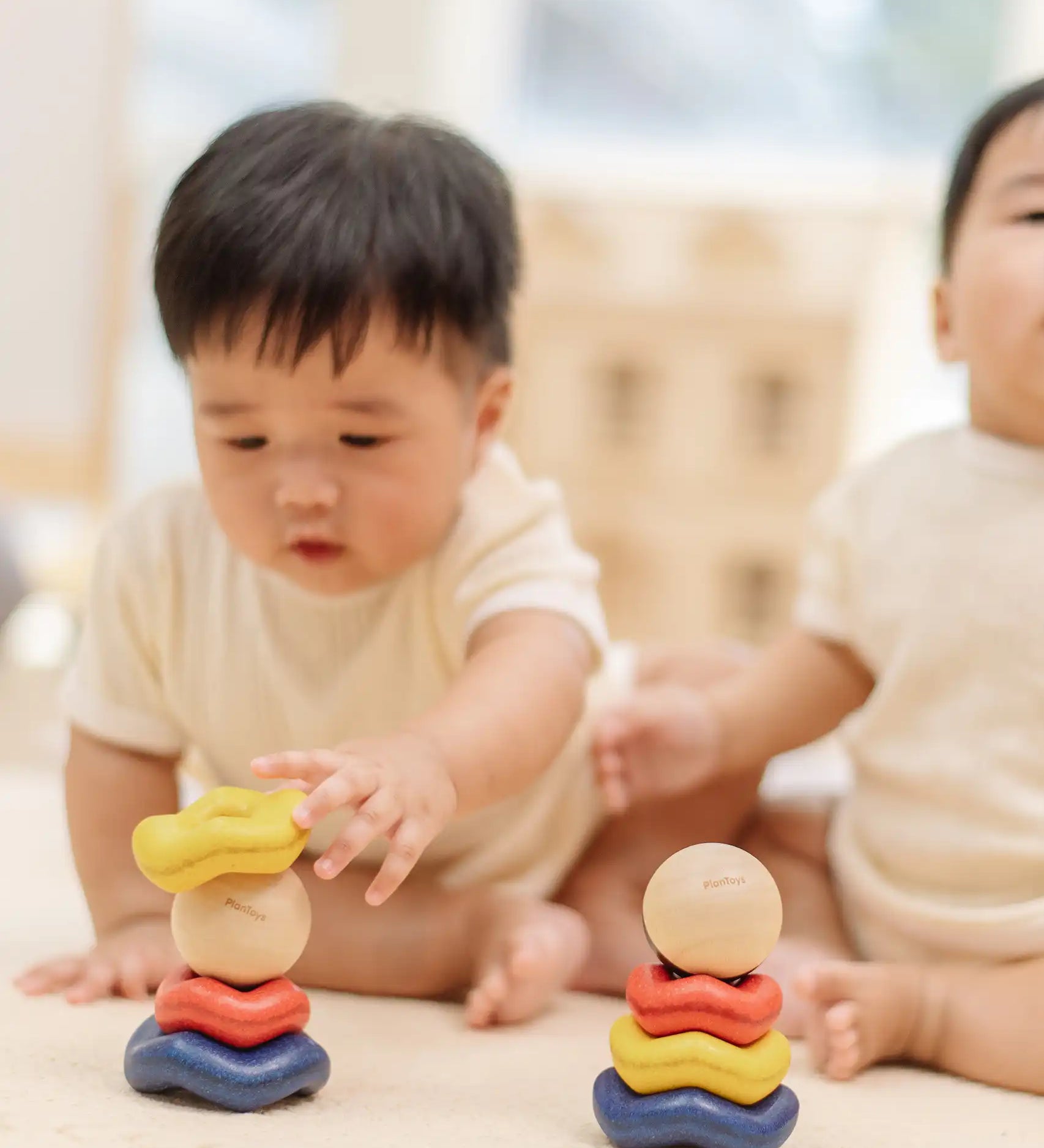 Baby playing with the PlanToys ball and wave stacker wooden baby stacking toy.