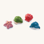 The Plan Toys sealife bath toys set includes a red shell, pink starfish, green turtle and blue dolphin. They are made from PlanWood, derived from rubberwood and are plastic free. They have two holes to release water. 