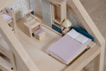 A close up of the bed from the PlanToys Bedroom Dolls House Furniture set placed in a room in a wooden dolls house. 