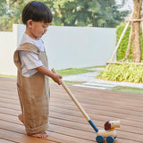 Child pushing the PlanToys push and pull puppy wooden toy along with the stick attachment.