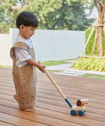 Child pushing the PlanToys push and pull puppy wooden toy along with the stick attachment.