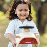 Child carrying the PlanToys Driving Console wooden toy in their hands.