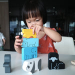 Girl stacking pieces of the Plan Toys plastic free wooden animal puzzle on a white table