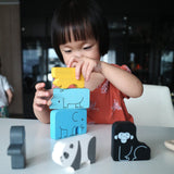 Girl stacking pieces of the Plan Toys plastic free wooden animal puzzle on a white table