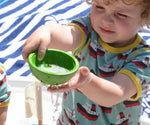 A child playing with the green bowl from the PlanToys Fountain Bowl Set, water can be seen pouring from the holes in side of the bowl.  
