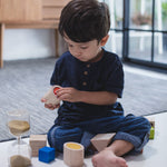 A child sitting on a floor playing with the PlanToys Geo Matching Blocks. 