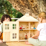 Children playing with the PlanToys wooden Georgian dollhouse children's toy. The house has been filled with dolls house furniture.