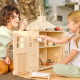 Children playing with the PlanToys wooden Georgian dollhouse children's toy. The house has been filled with dolls house furniture.