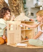 Children playing with the PlanToys wooden Georgian dollhouse children's toy. The house has been filled with dolls house furniture.