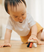 A baby placing their hand on the PlanToys Flexi Jellyfish wooden high contrast baby toy. A wooden top with high contrast, white, greys, black and red flexible wooden pieces for the jellyfish legs. PlanToys range of toys are made from sustainably sourced rubberwood, we're proud stockists of PlanToys here at Babipur.  