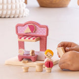 Child playing with the PlanToys ice cream shop wooden toy playset, placing the advert board into the scene.